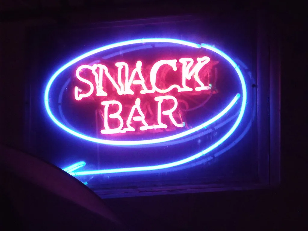 Pink and blue neon sign glowing against a dark wall