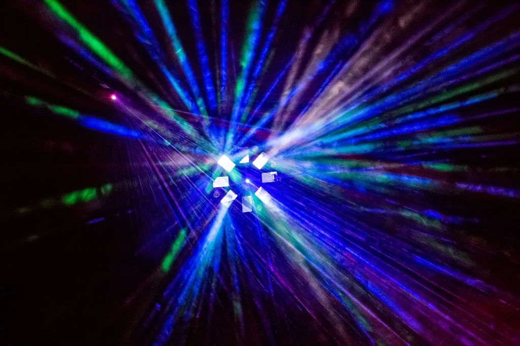 Colourful disco light beams spreading across a dark party room