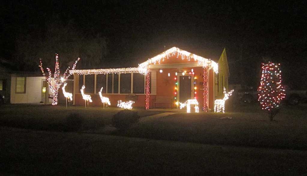 House outlined with Christmas lights, with lit reindeer figures on the lawn
