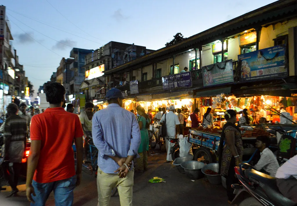 Busy market street at dusk with brightly lit shops